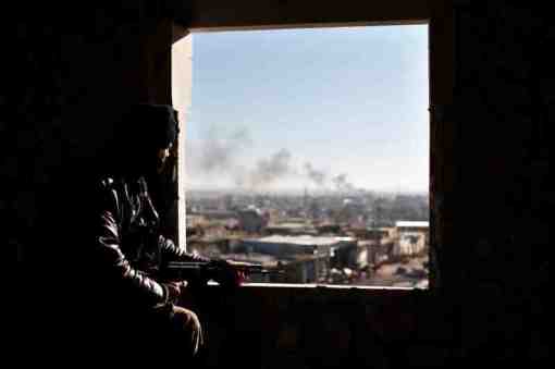 A Free Syria Army fighter watches from his position as smoke during a fight with forces loyal to President Bashar al Assad at the front line in Aleppo